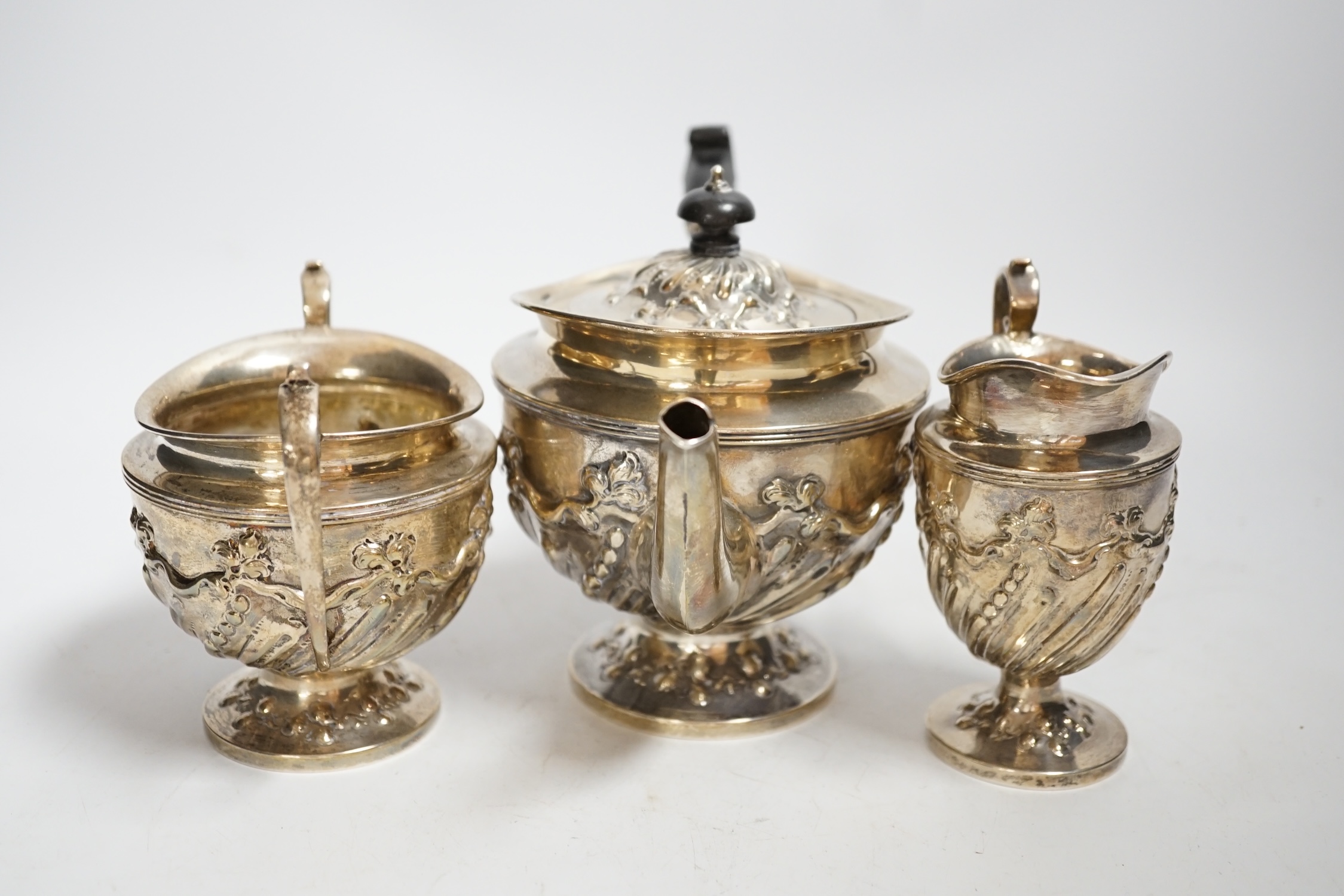A late Victorian repousse silver three piece bachelor's tea set, double stamped maker's marks, London, 1890, gross weight 21.8oz.
